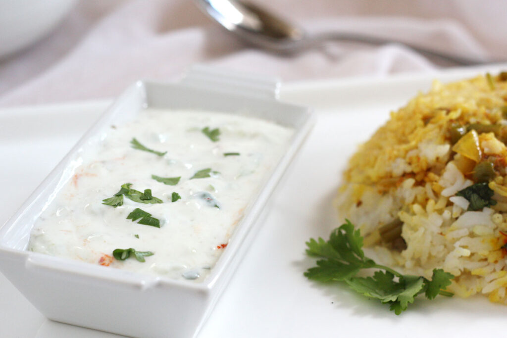 Cucumber raita served next to biryani.