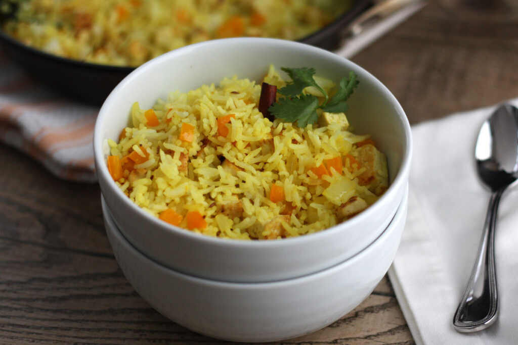 Two stacked bowls with fired rice on top bowl. Spoon at the side.