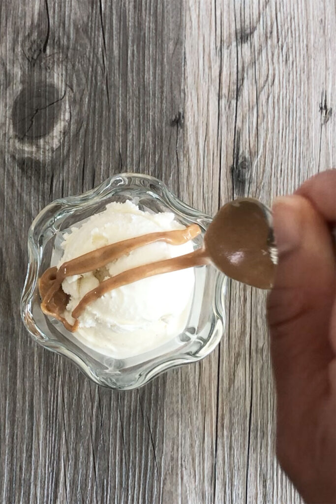 Peanut Butter being drizzled over vanilla ice cream.