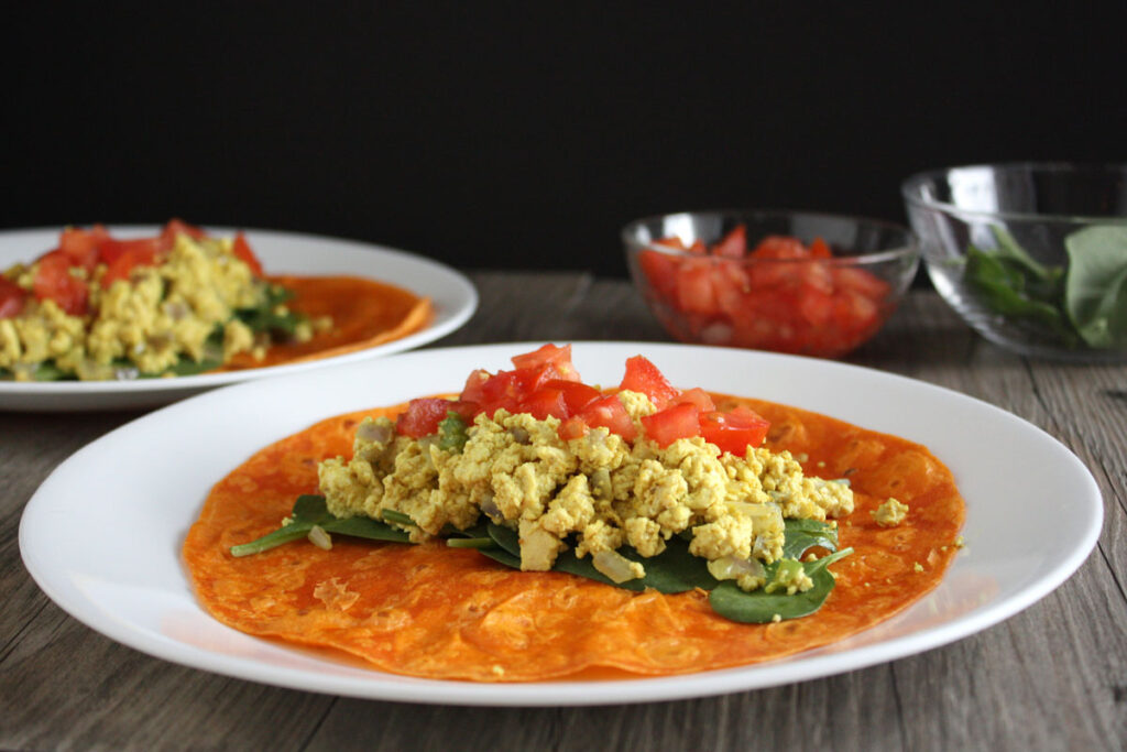 Tofu scramble wrap being assembled on plate.