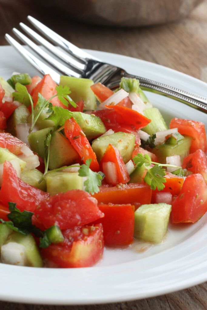 Close up view of tomato and cucumber salad in plate.