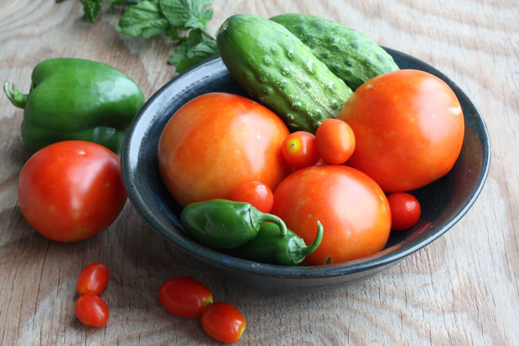 Fresh tomatoes, cucumbers and jalapenos in bowl.