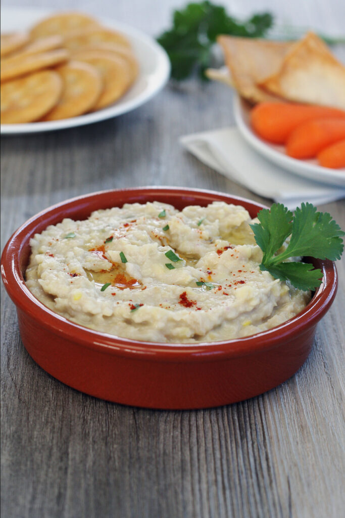 White Bean Dip with crackers and carrots in background.