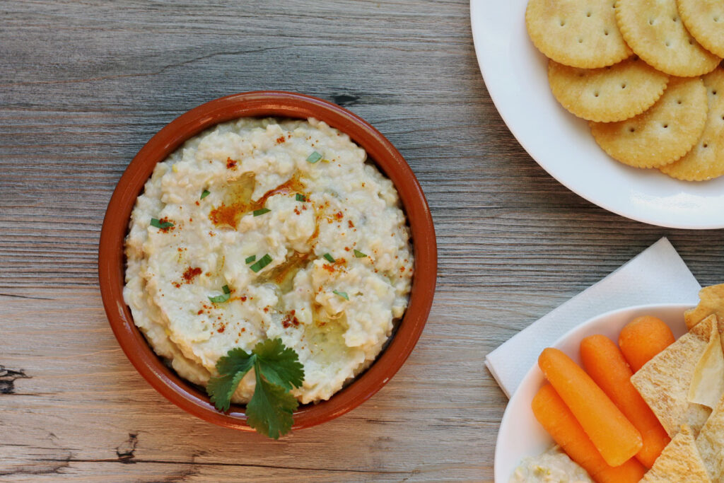 Top view of white bean dip with carrots and crackers.