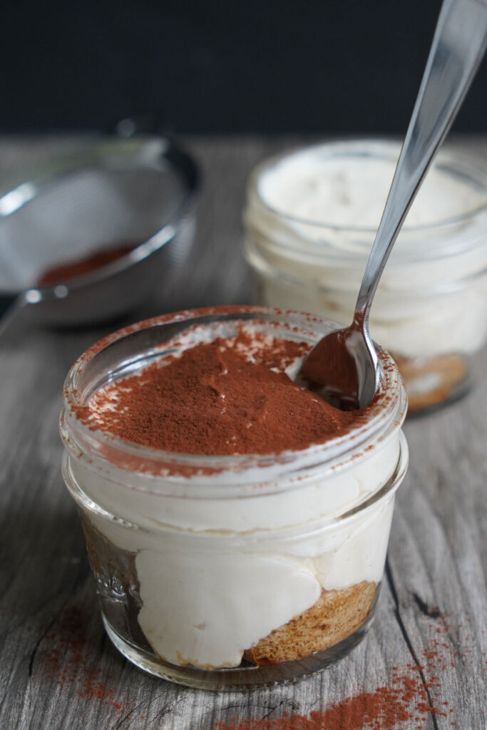 Tiramisu in a jar with spoon.