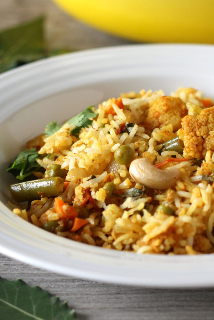 Closeup view of biryani showing rice, vegetables and cashews.