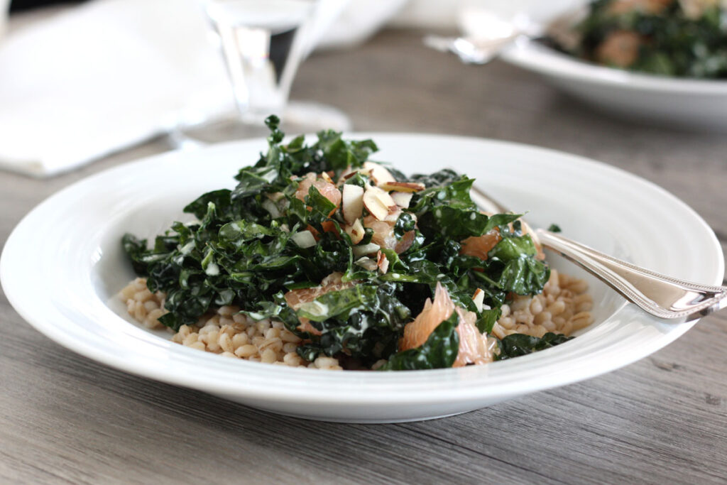Kale and barley salad in a white plate with spoon.