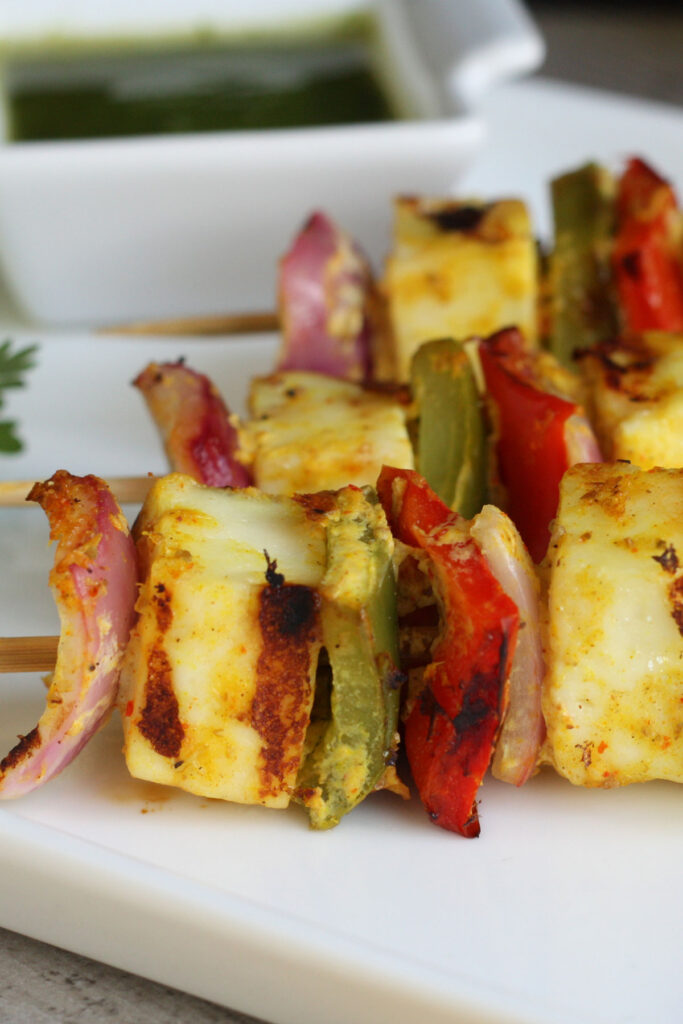 Close up of paneer vegetable kabobs on skewers.