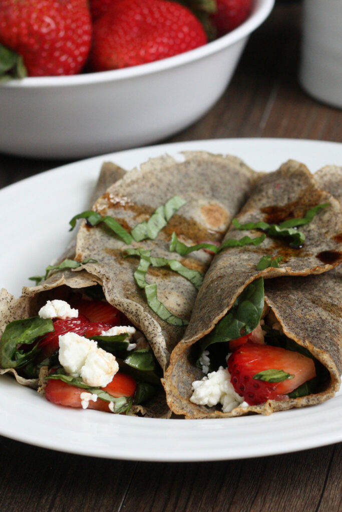 Two buckwheat crepes filled with strawberry spinach filling. Close up.