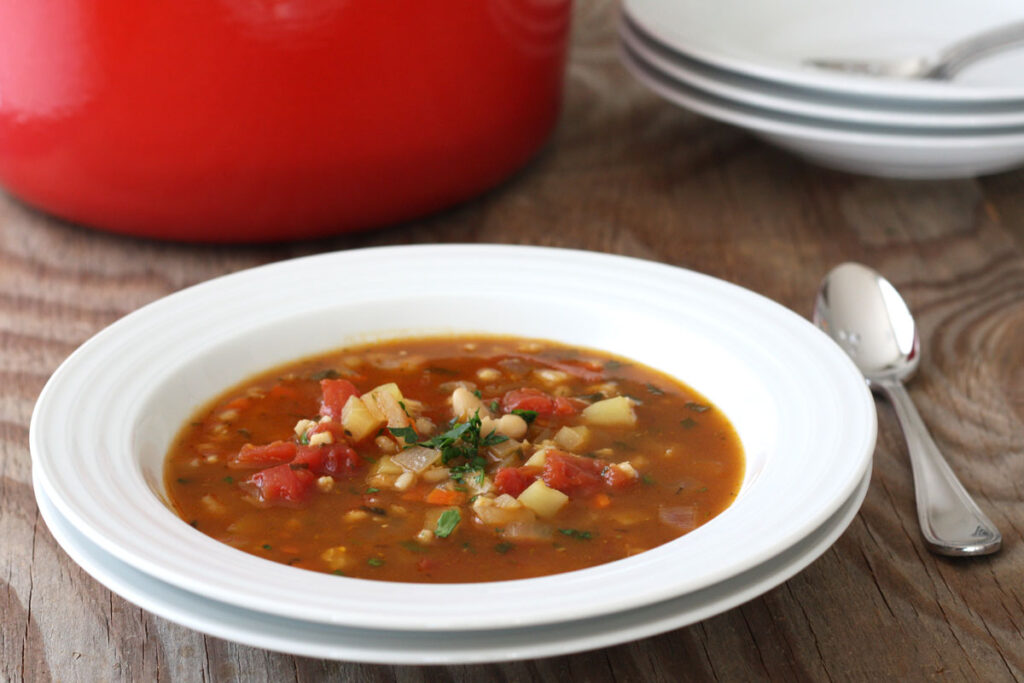 Vegetable barley soup in white plate.