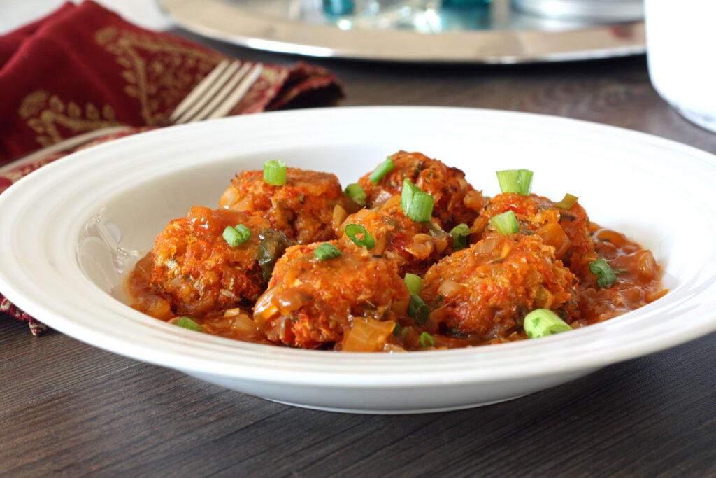Baked Cabbage Manchurian with sauce in white plate with fork.