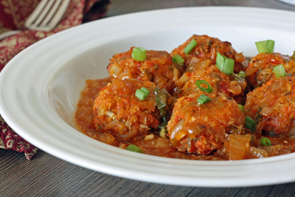 Baked vegetable Manchurian with sauce in white plate.