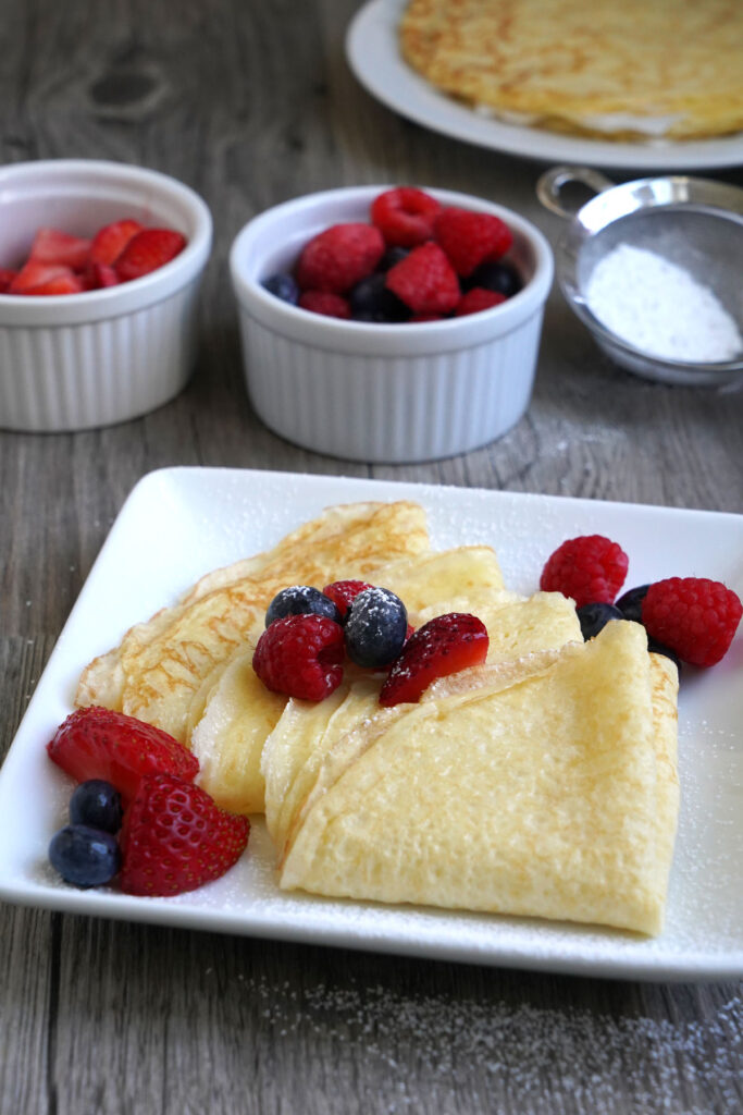 Crepes folded into a triangle, sprinkled with powdered sugar and served with fresh fruit. 