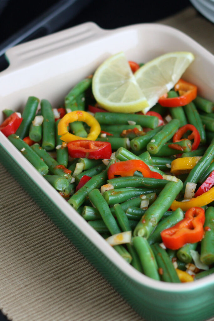 Green Bean Salad served in a smal casserole dish with lemon garnish.