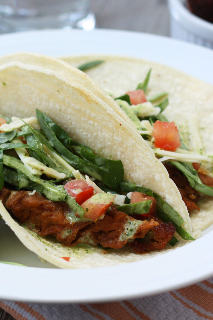 Seitan tacos close up in a white plate.