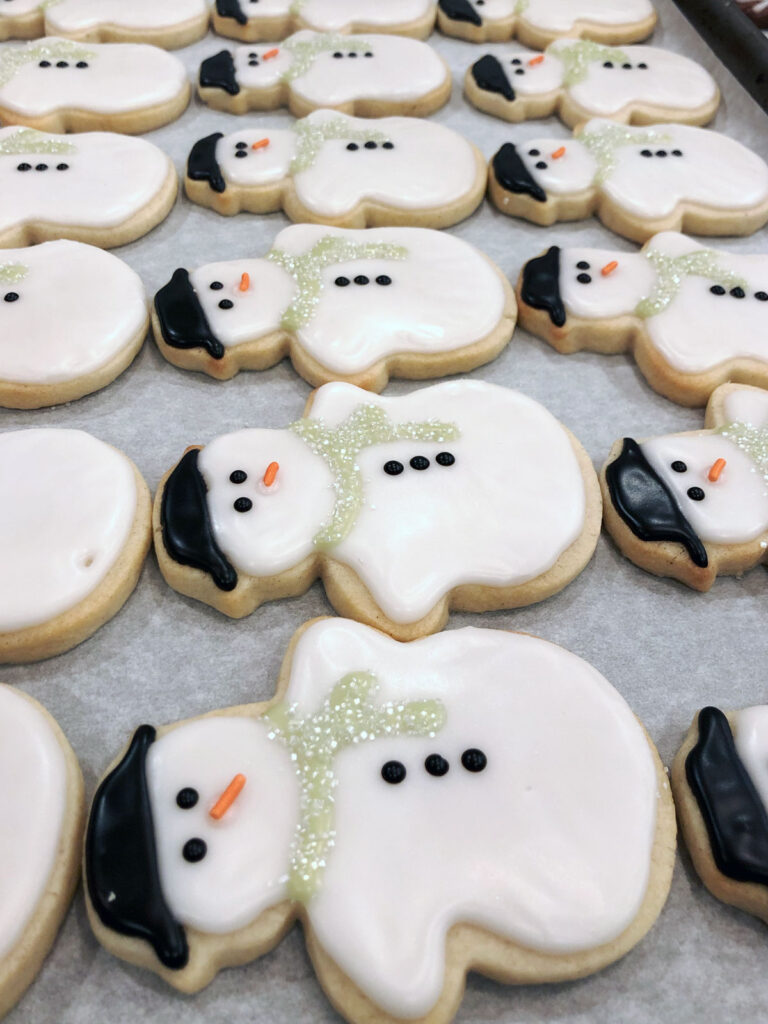 Finished snowman cookies drying in a sheet pan.