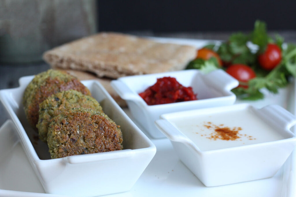 Baked falafel patties served with tahini sauce and hot sauce.