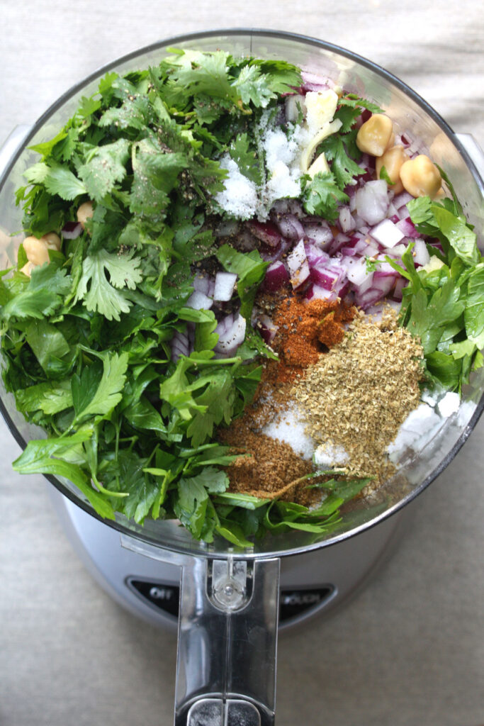 Ingredients for falafel patties in food processor container. 