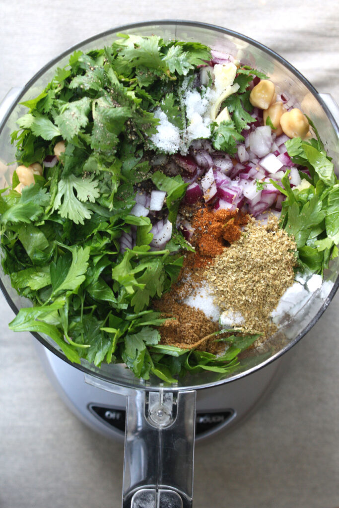 Ingredients for falafel patties in food processor container.
