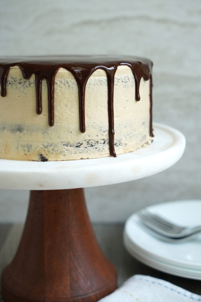 Mexican Chocolate cake with espresso buttercream on a marble cake stand with a wooden base.