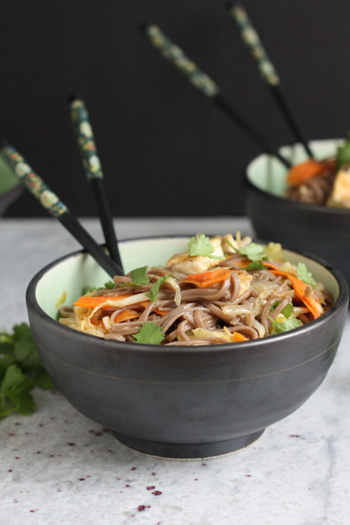 Close up of Sesame noodles in a bowl with chopsticks.