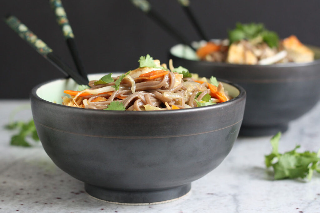 Sesame noodles in a bowl with chopsticks.