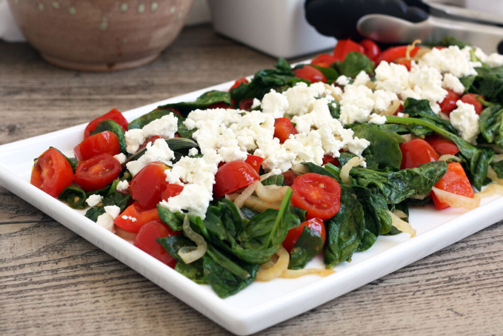 White platter with spinach salad.