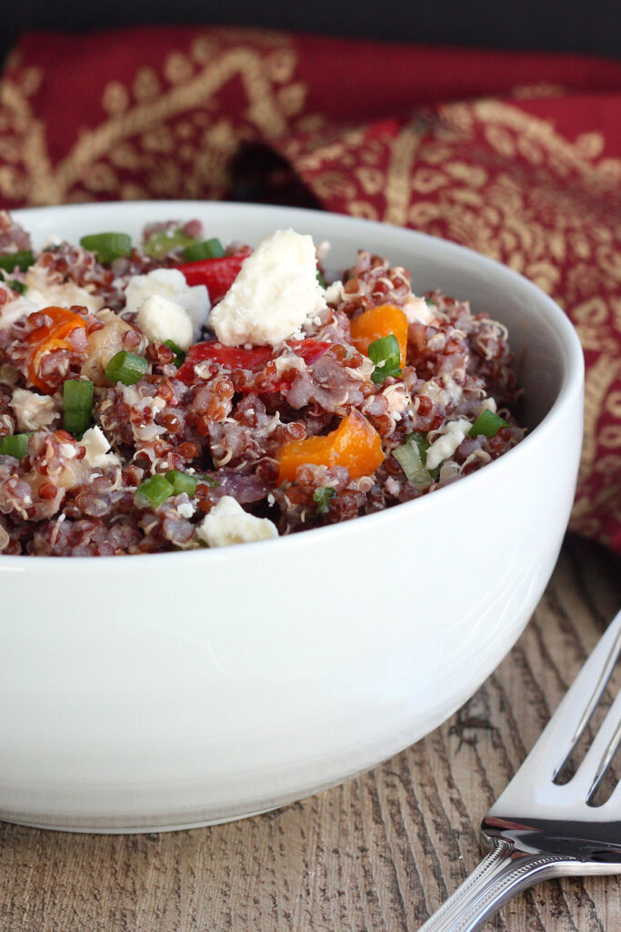 Quinoa salad closeup in a white bowl with red napkin and fork to the side. 