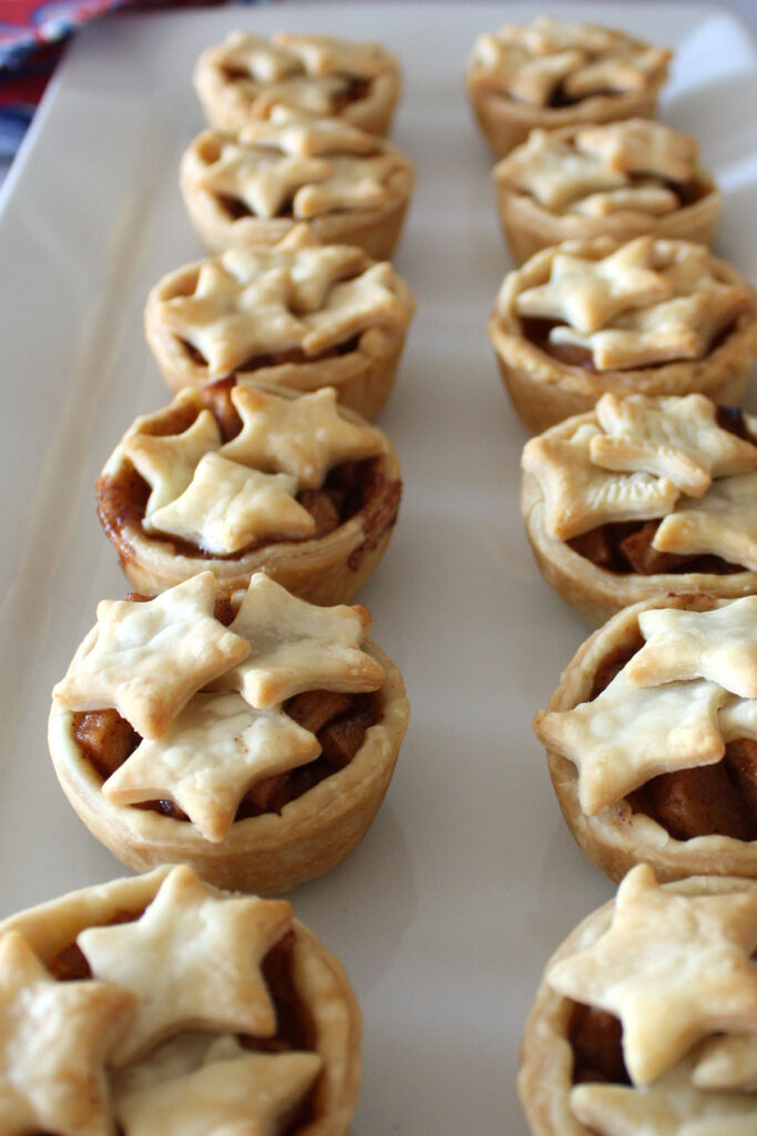 Mini apple pies with star decorations on a white platter.