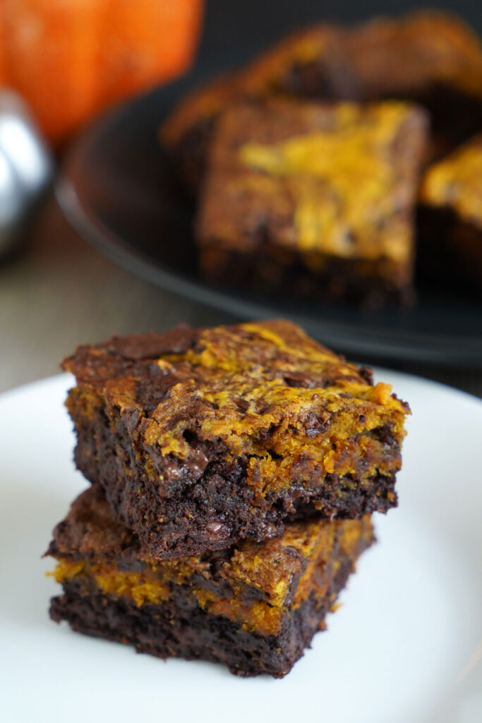 Two pumpkin brookies stacked on a white plate.