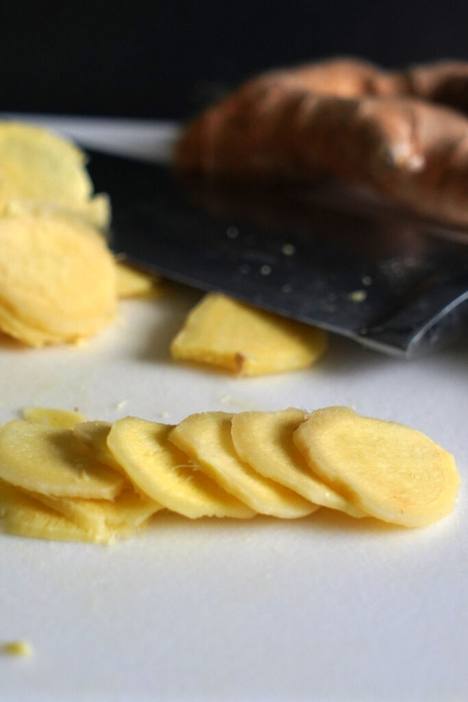 Fresh ginger slices on a cutting board.