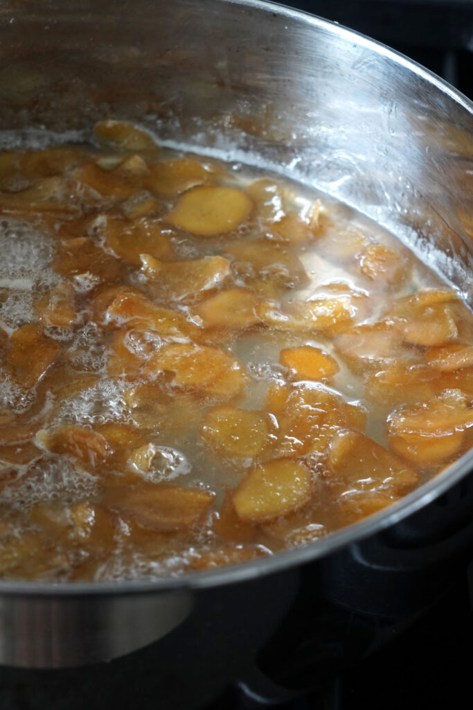 Ginger slices simmering in sugar water.