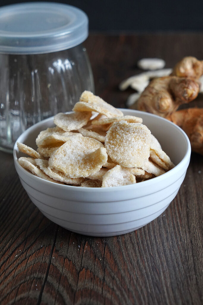 Crystallized candied ginger slices in a white bowl.