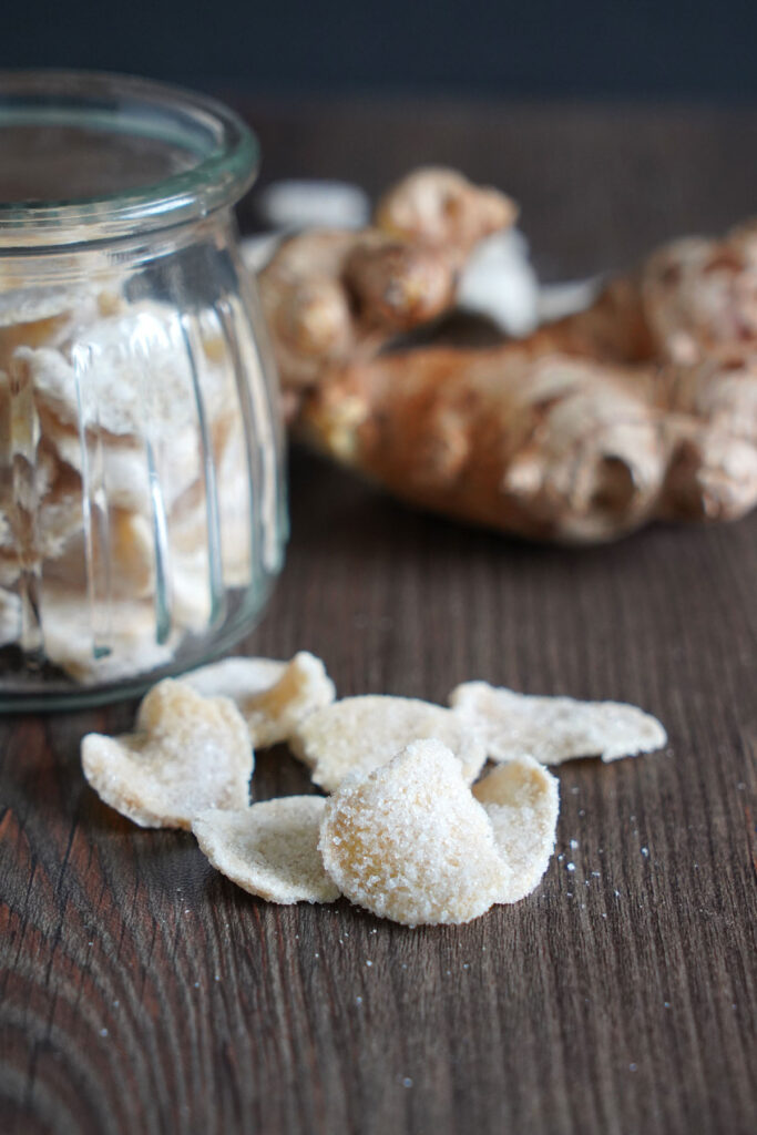 Candied ginger slices with jar in background.