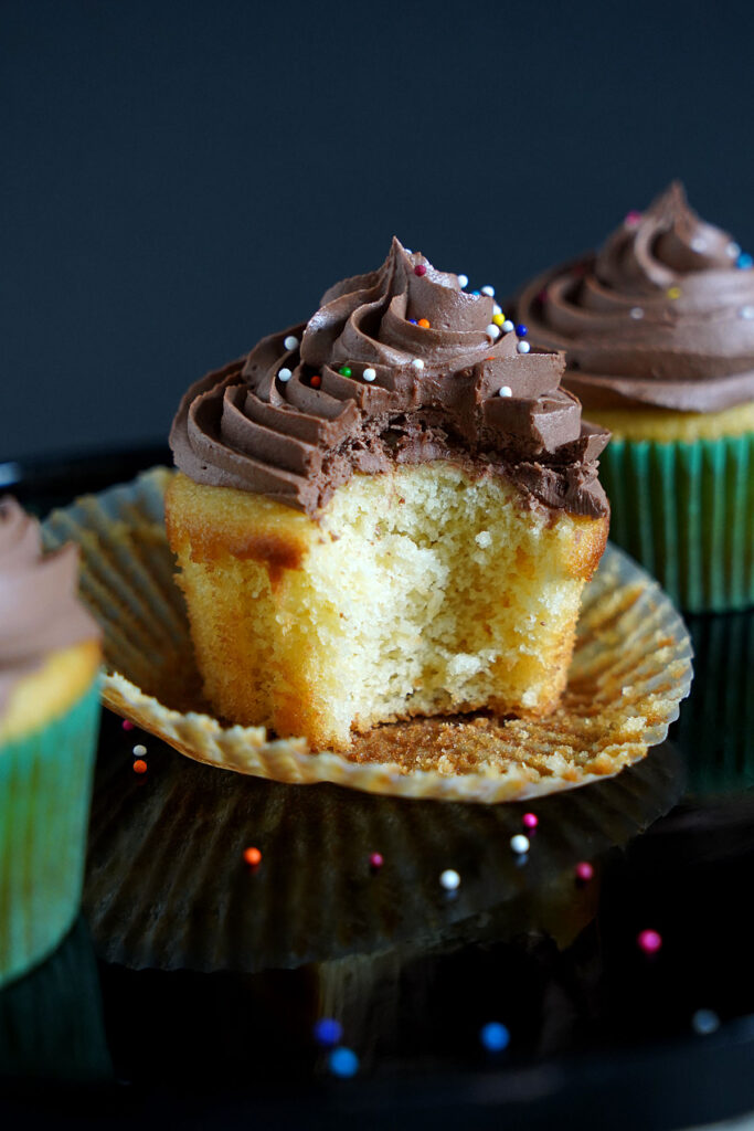 Chocolate frosted vanilla cupcake with a bite taken.