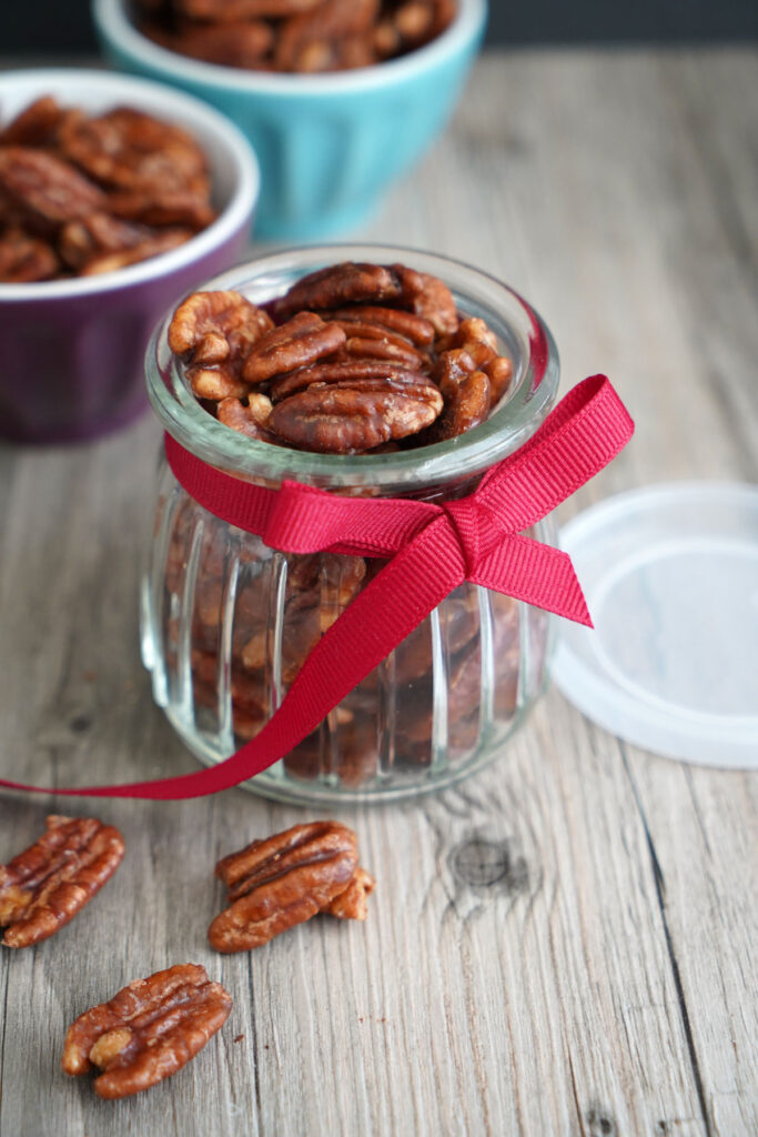 Candied pecans in small jar with red ribbon.