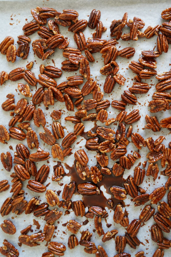 Candied pecans drying on parchment.