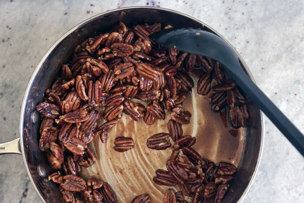 Pecans being coated with sugar spice mix.