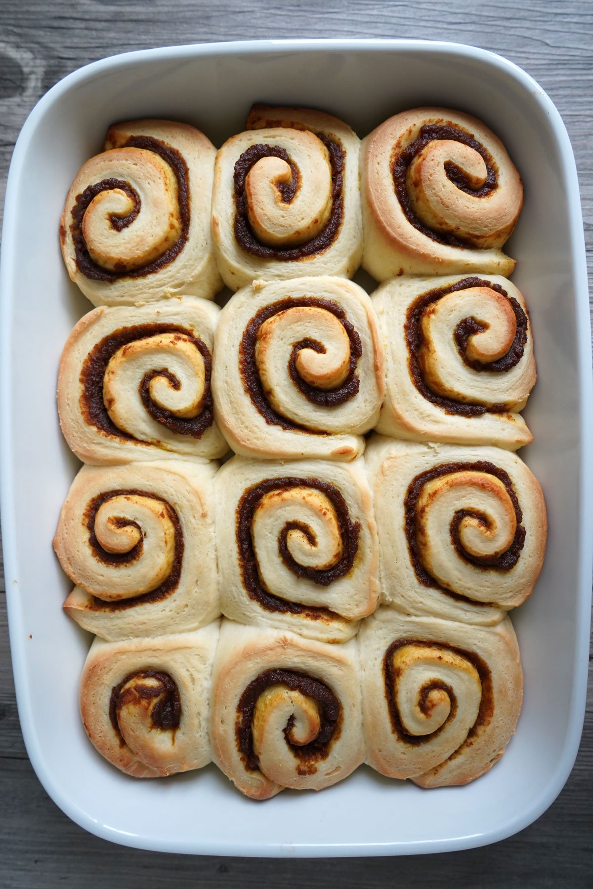 Baked pumpkin spice cinnamon rolls in baking dish.