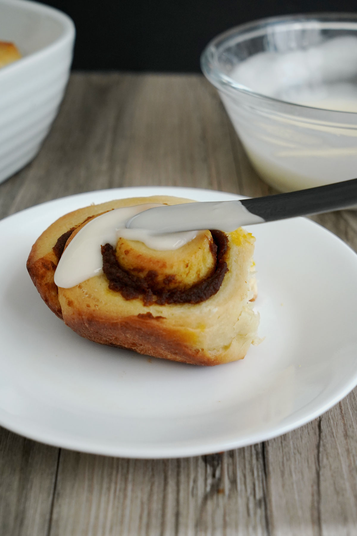 Glaze being spread on top of pumpkin cinnamon roll.