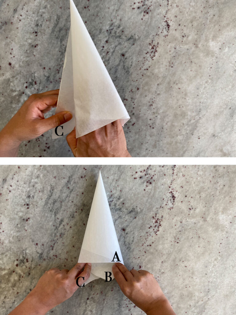 Final steps of parchment triangle being rolled into cone shape.