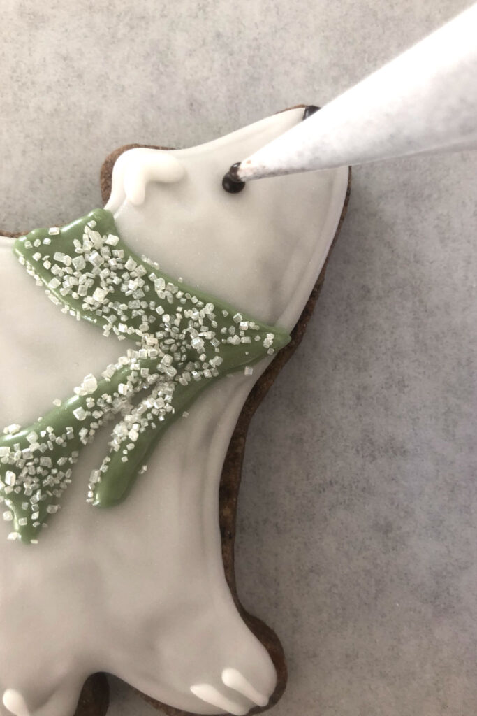 Polar Bear shaped cookie being decorated using a parchment cone.