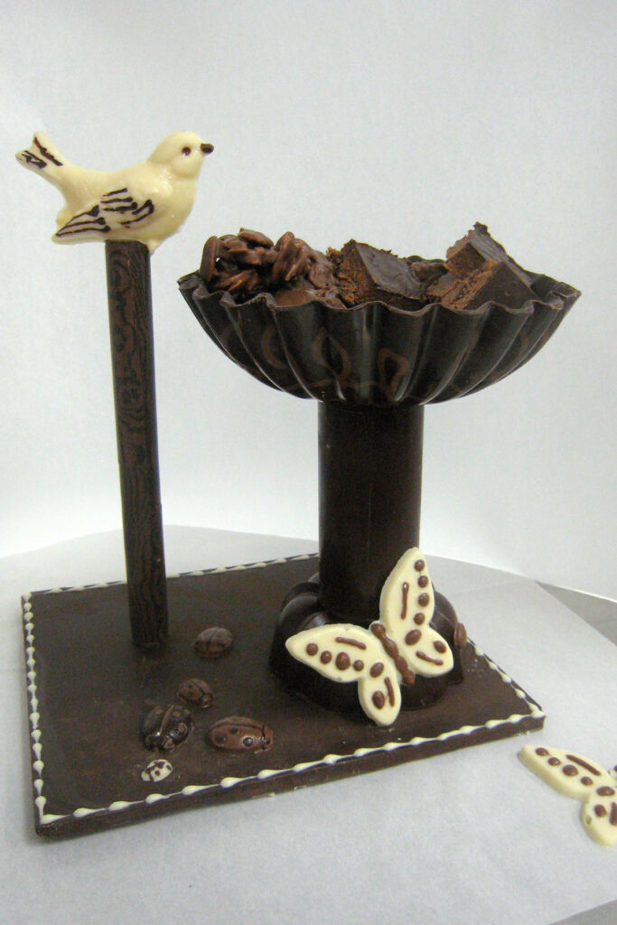 Chocolate sculpture of bird and bird bath made with tempered chocolate.