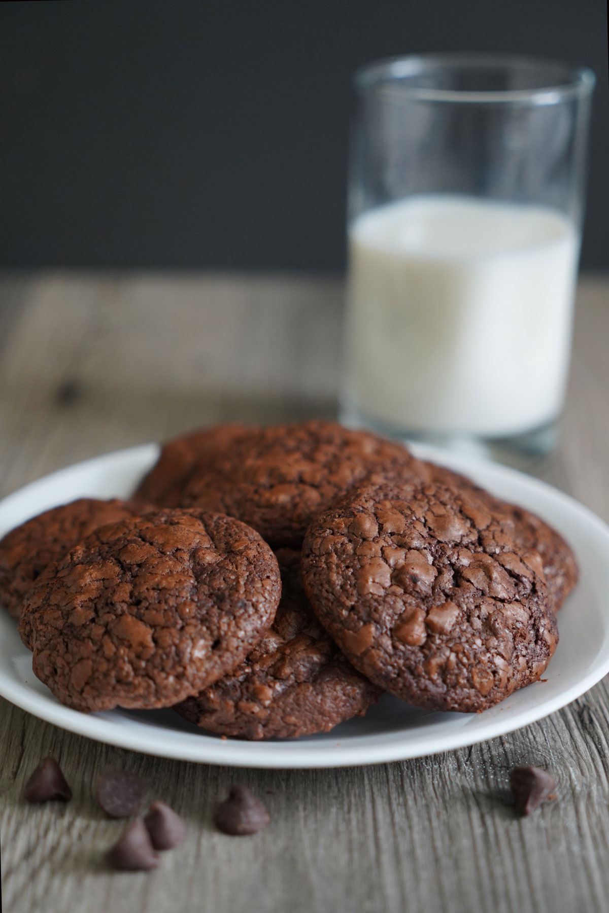 Brownie cookies on a white plate with glass of milk.