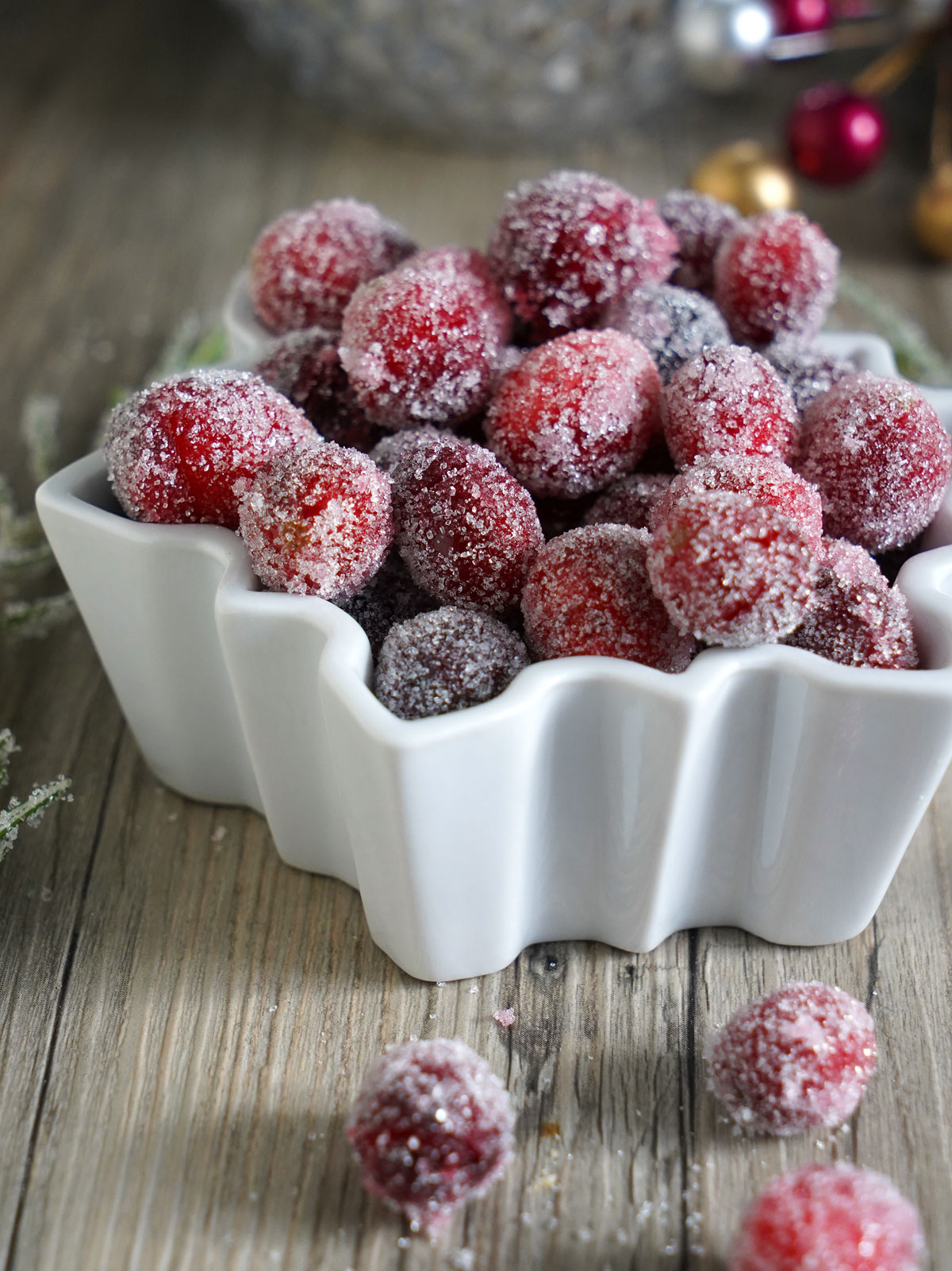 Sugared cranberries in snowflake shaped white bowl.