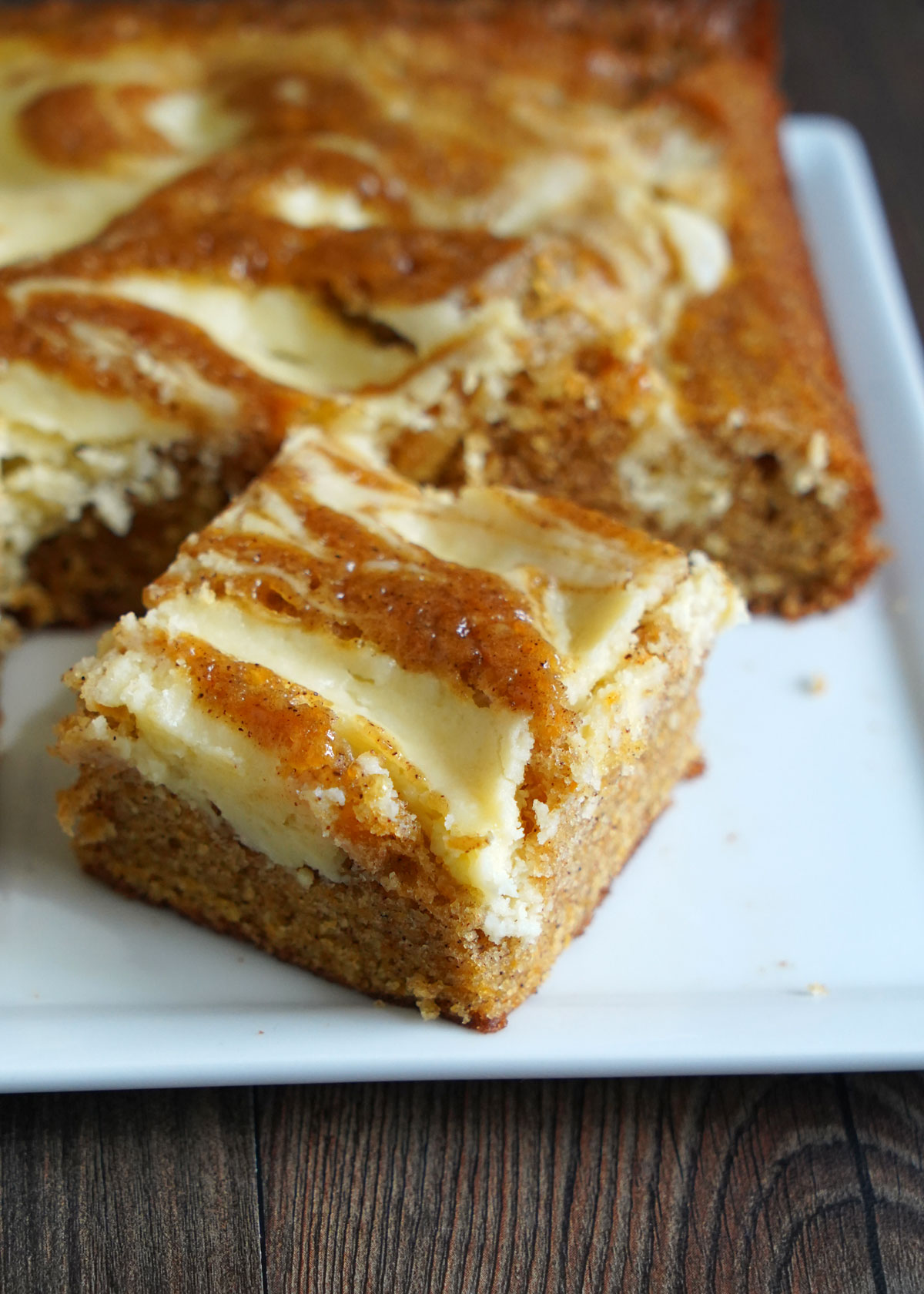 Cut out pieces of carrot cake cheesecake on white platter.