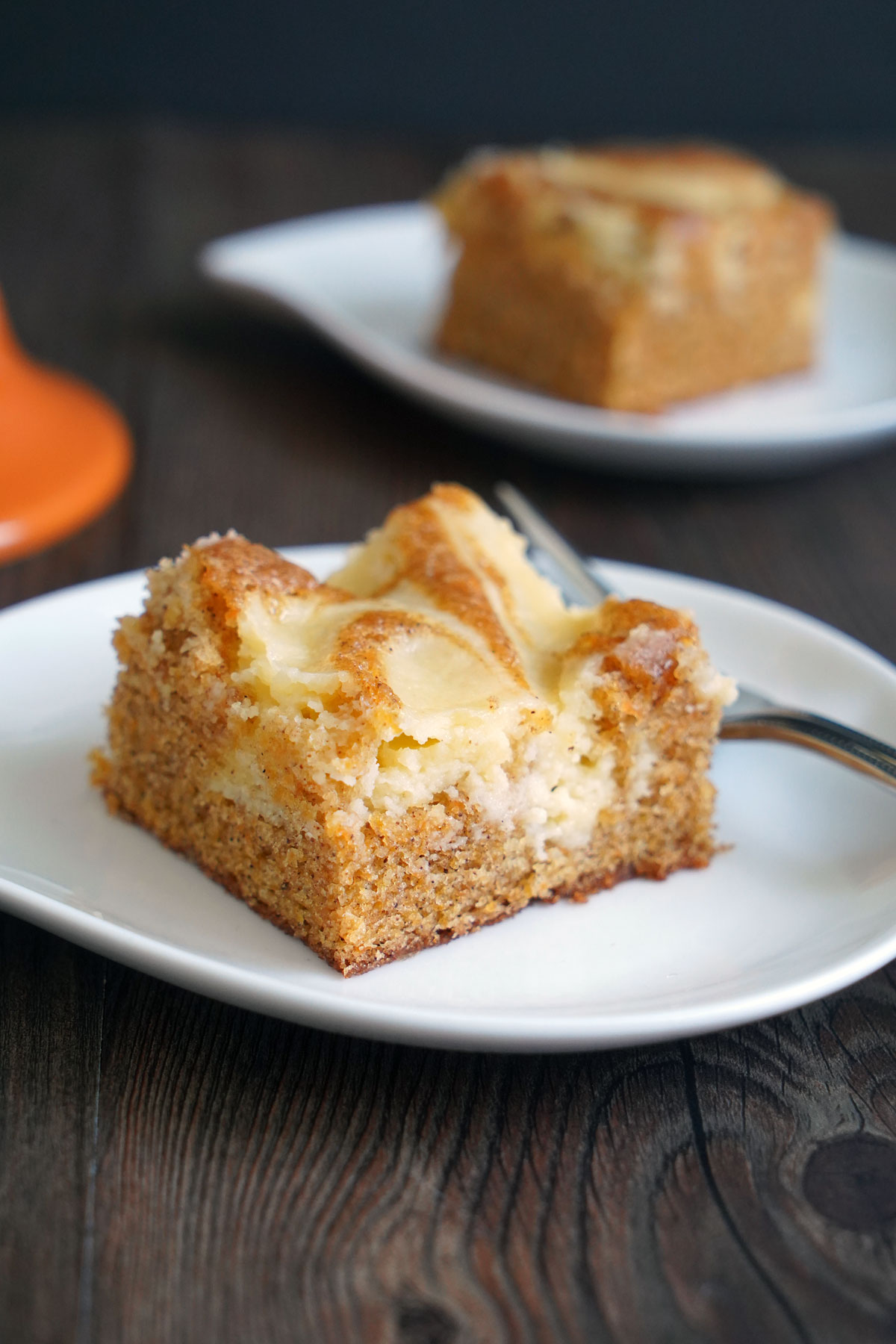 Slice of carrot cake cheesecake in white plate with fork.