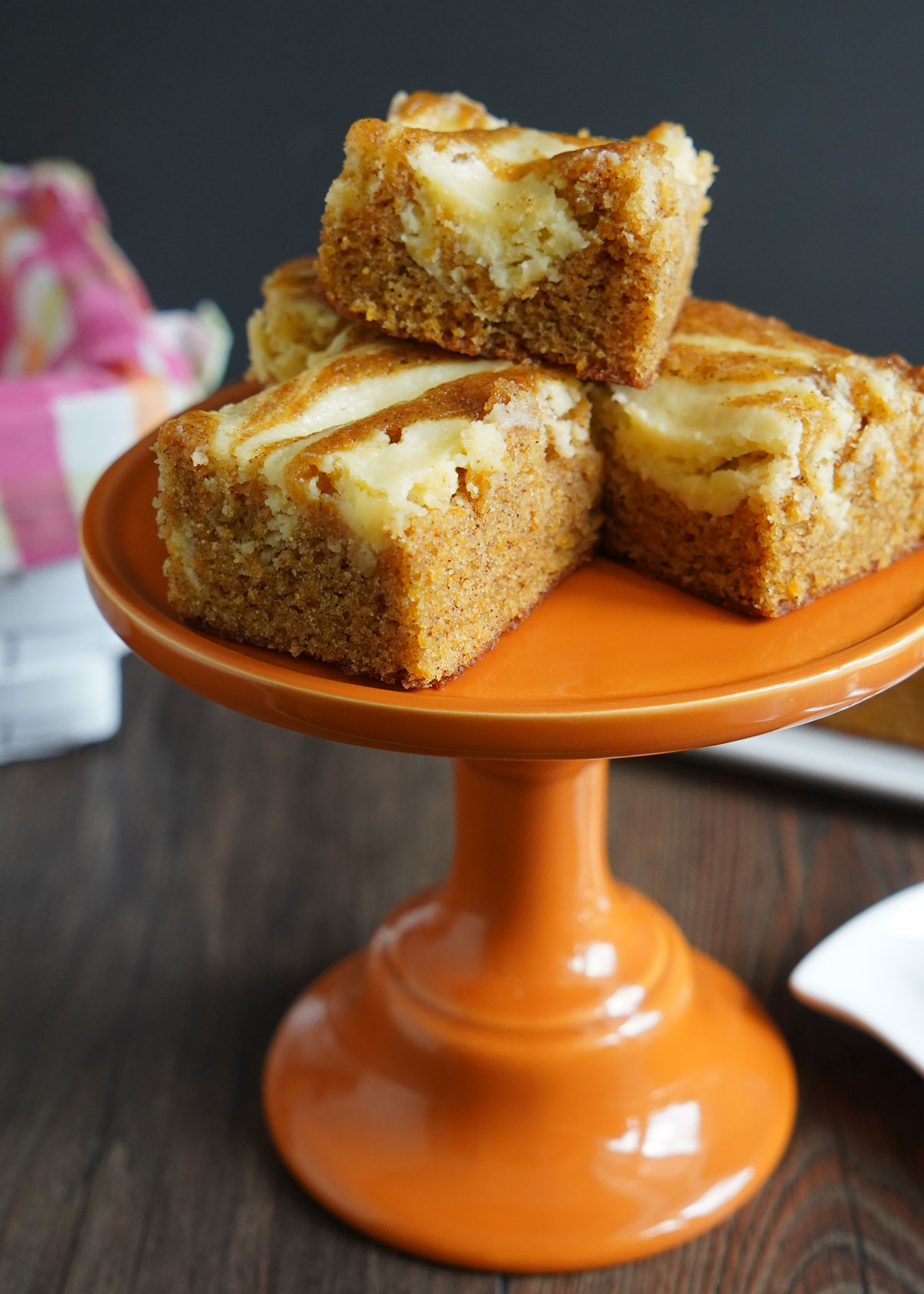 Carrot cake cheesecake slices on an orange pedestal