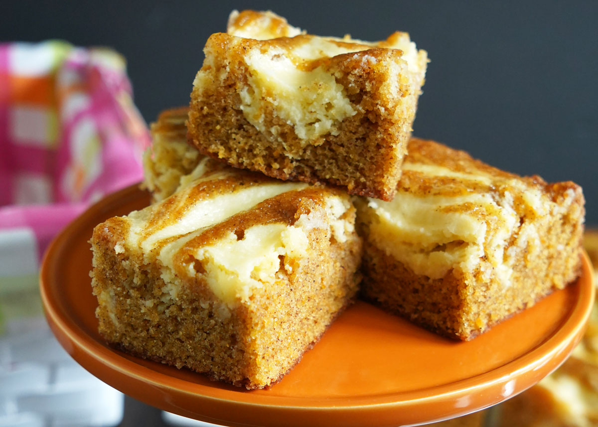 Closeup view of carrot cake cheesecake on orange pedestal.