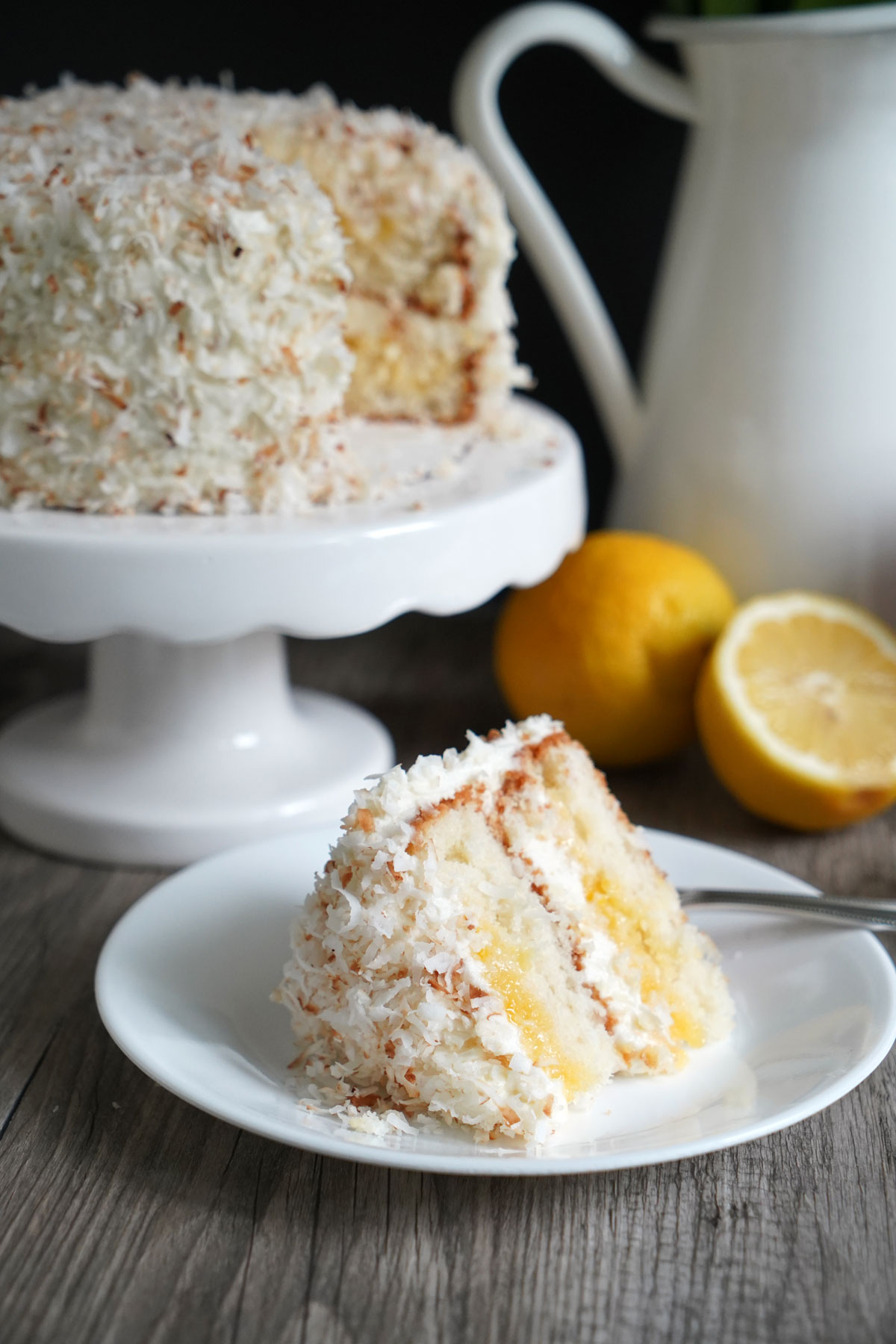 Cake slice in white plate with cut cake in background.